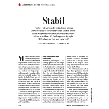 Verschmutzte weiße Tasse liegt auf einem Tisch mit Kaffeeflecken, daneben Text über Küchenrollen aus Recyclingpapier und deren Stabilität im Öko-Test Magazin.